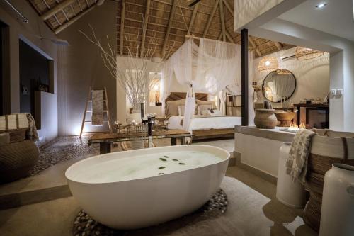 侯斯普瑞特African Flair Boutique Safari Lodge的带浴缸的浴室和卧室