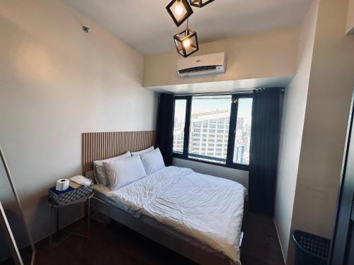 马尼拉Heart of Makati, Fully furnished condo, cbd central location的窗户客房内的小床