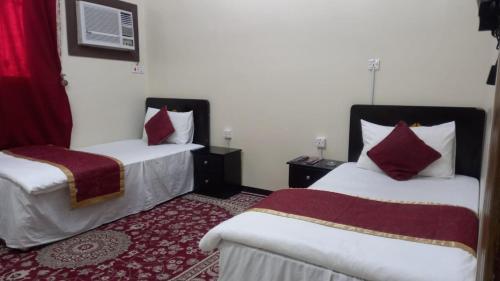 Al Nairyahالعييري للشقق المفروشة النعيريه 4的酒店客房 - 带两张带红色枕头的床
