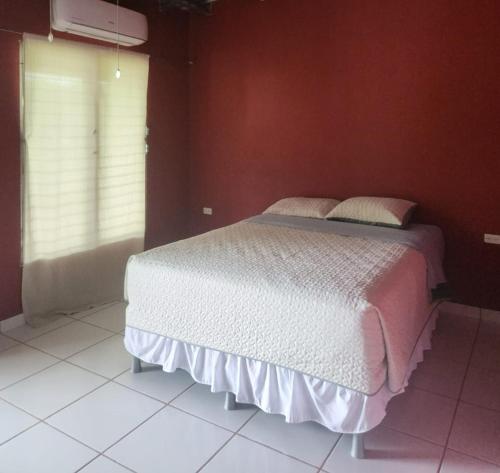 科马亚瓜Aparta Hotel Palmerola的卧室配有红色墙壁上的白色床
