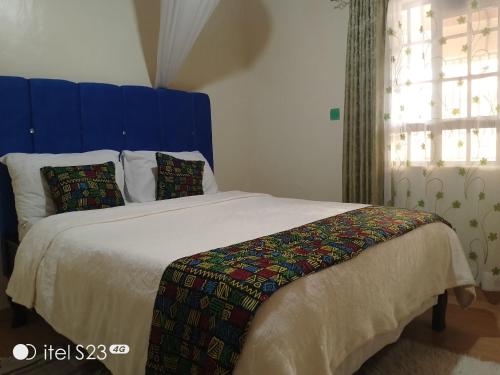 KakamegaMaridadi place的一间卧室配有一张大床和蓝色床头板