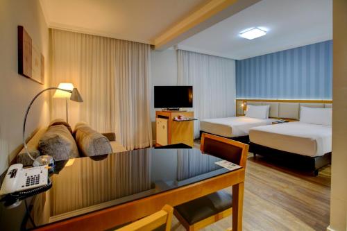 圣保罗Quality Suítes Oscar Freire的酒店客房配有两张床和一张书桌
