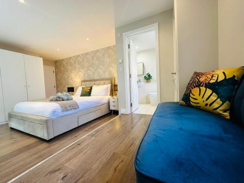 伦敦Stylish, modern appartment in Central London的一间卧室配有两张床和蓝色的沙发
