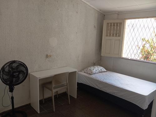 特雷西纳Hostel Teresina的一间卧室配有一张床、一张书桌和一个窗户。
