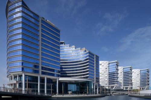 迪拜Marriott Marquis Dubai的一座高大的建筑,有蓝色的窗户,位于城市
