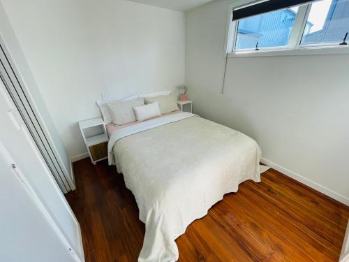 纳皮尔Sunny Modern Cottage - Close to Airport的白色的卧室设有床和窗户