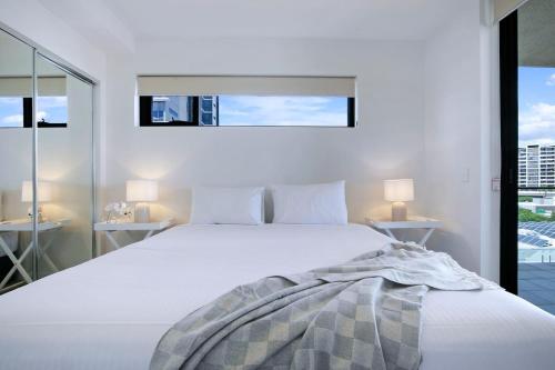 布里斯班Regatta Hideaway - A Breezy Balcony Residence的卧室配有一张带两张桌子的大型白色床