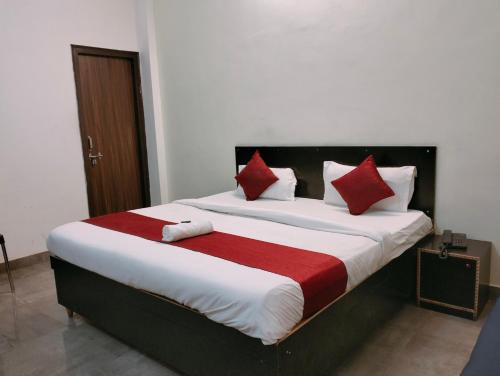 勒克瑙The Champ Palace的一间卧室配有一张带红色和白色枕头的大床