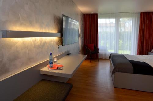 埃格尔金根Hotel Egerkingen, idealer Zwischenstopp的一间卧室配有一张床和一张带一瓶水的书桌。