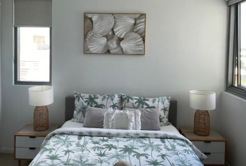 穆卢拉巴Nova Apartment Mooloolaba Beach的一间卧室配有一张带2个床头柜和2盏灯的床。