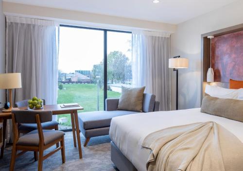 基督城Sudima Christchurch City的酒店客房配有一张床、一张桌子和一把椅子。
