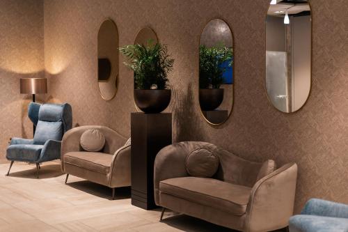 塞格德Hotel Gerardus的一间设有两把椅子和两面镜子的等候室
