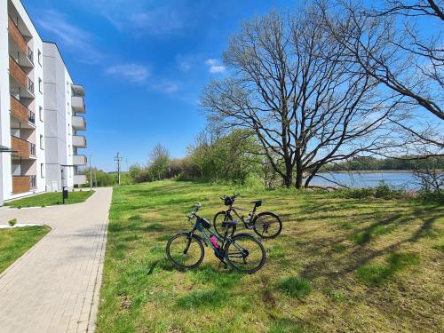 伊拉华Przystań Natura的两辆自行车停在大楼旁边的草上