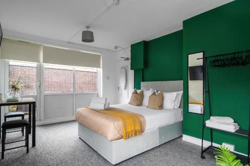 East BarnetLivestay Affordable En-Suite Studio Rooms in London, N14的绿色和白色的卧室配有床和书桌