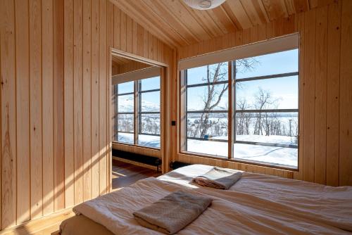 基尔匹斯扎我维Kalamaja Kilpisjärvi的一间带木墙的卧室和一张带两个窗户的床