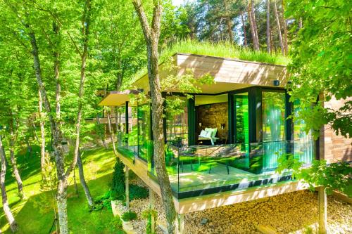 KojoriBioli Wellness Resort的树林中玻璃外墙的房子