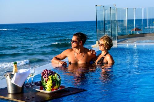 玛利亚Alexander Beach Hotel & Village Resort的男人和女人在海边的游泳池里