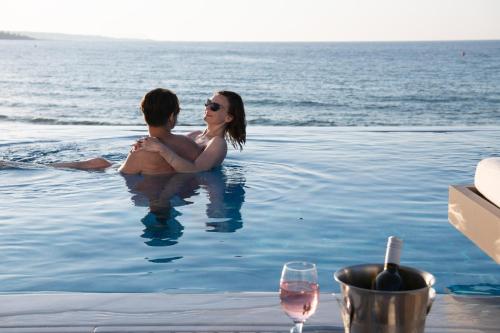 玛利亚Alexander Beach Hotel & Village Resort的坐在游泳池里的男人和女人