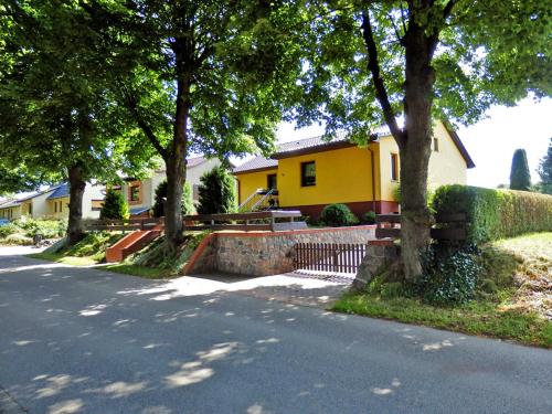 GotthunFerienwohnung unweit der Müritz的路旁有树木的黄色房子