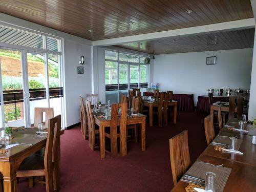 努沃勒埃利耶New Ashley Resorts (PVT) LTD的餐厅设有木桌、椅子和窗户。