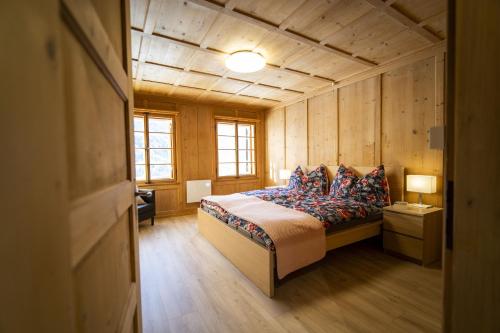 RamoschChasa Schilana 84的卧室配有一张床铺,位于带木墙的房间内