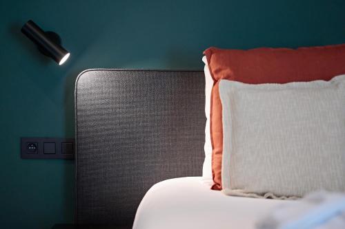 罗什福尔麦尔博斯特酒店的一张带橙色和白色枕头的床铺,靠墙
