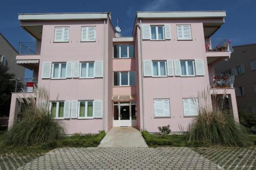 罗维尼萝拉公寓的粉红色的公寓楼,前面有车道
