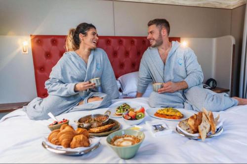 迪拜Hyatt Centric Jumeirah - Dubai Twin Room - UAE的坐在床上吃着食物的男人和女人