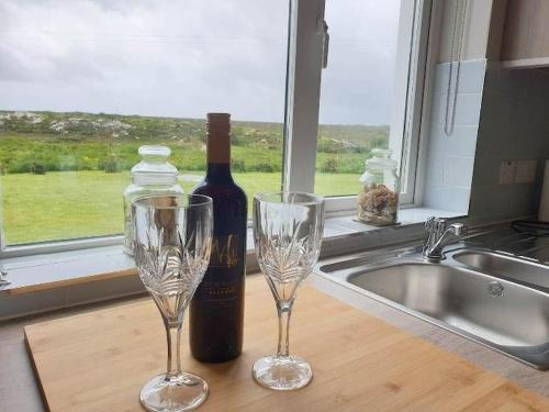 BallinaboyHillside House的厨房柜台上的一瓶葡萄酒和两杯酒杯