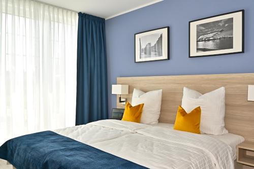 韦德尔HotelHafenWedel的一间卧室配有一张带蓝色墙壁和黄色枕头的床