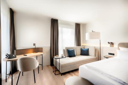 达姆施塔特Welcome Hotel Darmstadt City Center的酒店客房配有一张床、一张书桌和一张沙发。