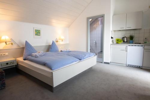 施瓦格明德Pension Krone的一间卧室配有一张蓝色床单,还设有一间厨房
