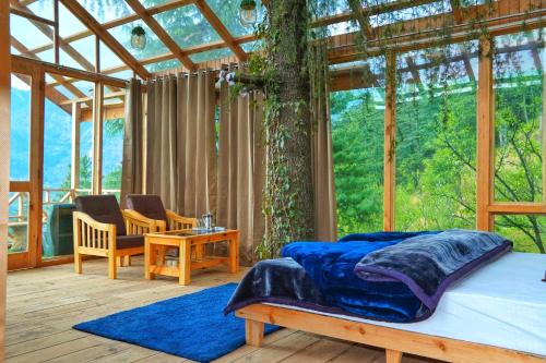 SainjStargazing Treehouse Himachal的一间玻璃房子内的卧室