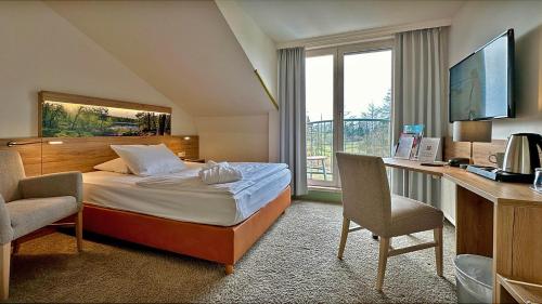 KremmenHotel & SPA Sommerfeld - Adults Only的配有一张床、一张书桌和一扇窗户的酒店客房