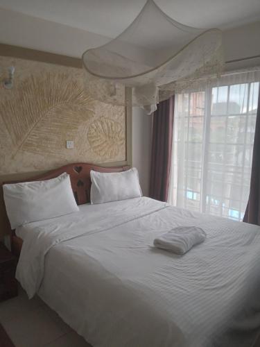 内罗毕Mvuli suites的卧室配有白色的床和大窗户