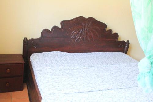 布琼布拉Kiriri SYMPA Home的卧室内的一张带木制床头板的床