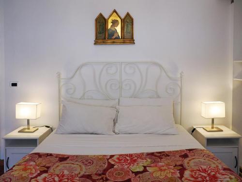 的里雅斯特达乐拉住宿加早餐旅馆的一间卧室配有一张带两盏灯的床,墙上挂着一张照片