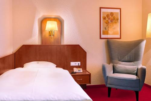 汉诺威Hotel Münkel的配有一张床和一把椅子的酒店客房