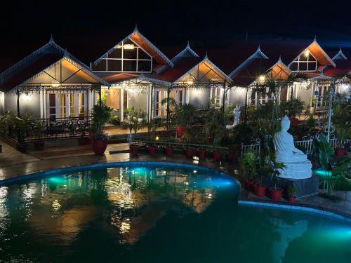 BāghdograYKC FARMS的一座晚上设有游泳池的房子
