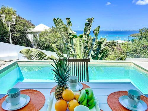 Anse Marcel Villa Romane private pool breathtaking sea view的一张桌子,旁边放着一碗水果