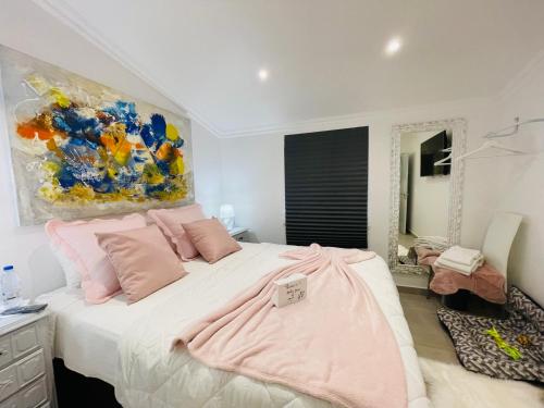 阿玛考德佩拉Kerart House的一间卧室配有带粉红色枕头和绘画的床。