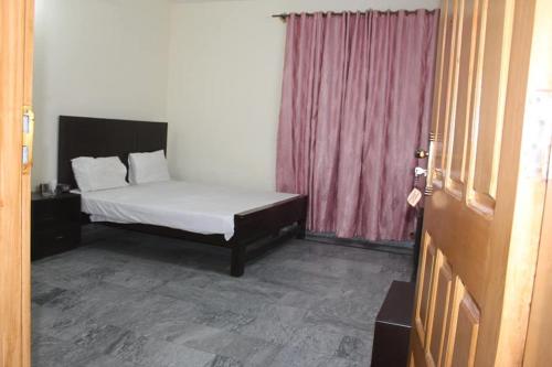 穆扎法拉巴德Kashmir Inn Hotel的一间卧室配有一张床和粉红色窗帘