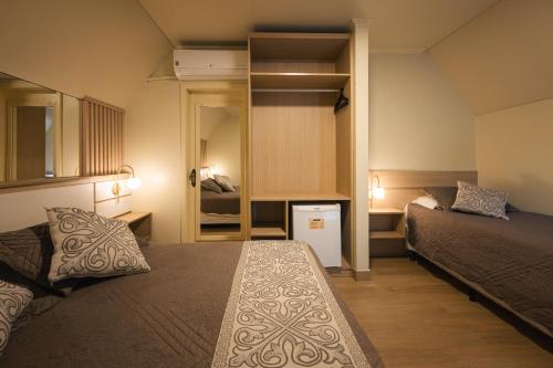 卡内拉Hotel Cabanas Alto Da Serra的小房间设有两张床和镜子