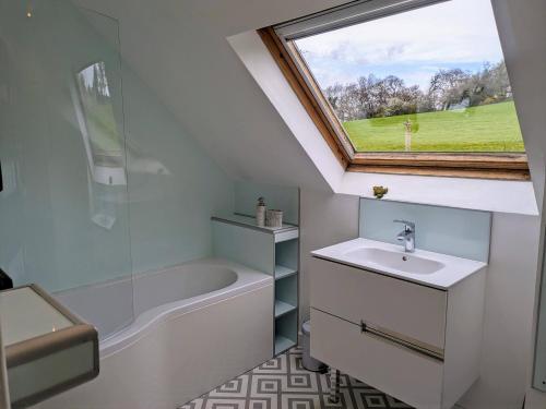 Cwm-y-gloTy Madog的一间带水槽和浴缸的浴室以及窗户。