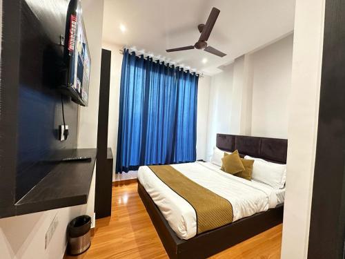 阿姆利则Hotel The Restu And Restaurant 300 Meter From Golden Temple的一间卧室配有一张带蓝色窗帘的床和电视。