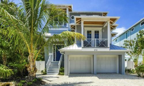 安娜玛丽亚Anna Maria Beach House, 5 beds 6,5 baths, roof-top deck and pet-friendly!的海滩上一棵棕榈树的房子