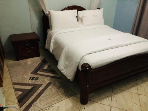 卡巴莱Gorilla Homestay Kabale的一张带白色床单和枕头的床以及床头柜