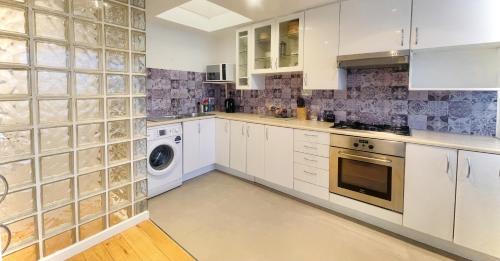 伦敦Newly Renovated 2BR Apartment in the heart of London的厨房配有白色橱柜、洗衣机和烘干机