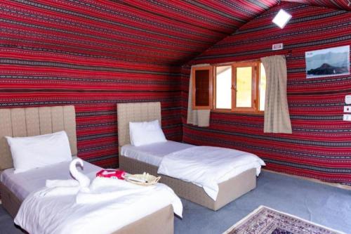 瓦迪拉姆Wadi Rum Sights Camp的红色墙壁的客房内的两张床