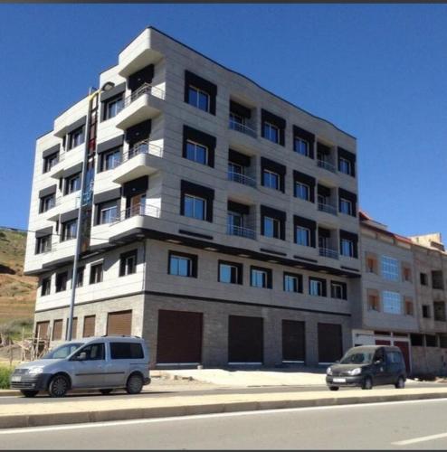 胡塞马Apartments Palace Rif Al Hoceima的两辆汽车停在一座大建筑前面